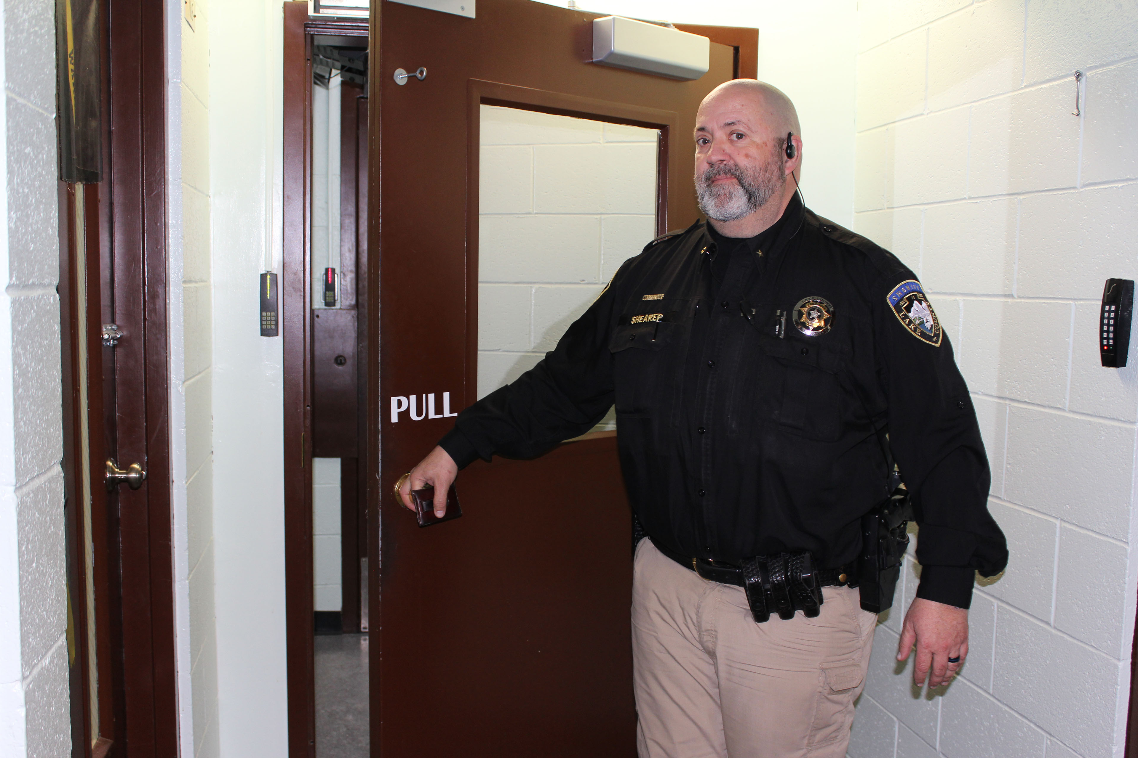 A police officer opens a door that leads to a hallway in a prison.